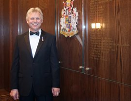 The food and beverage manager smiling in front of the Royal Canadian Military Institute crest.